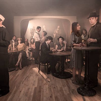 Men and women in classy dress, with styles from a 1940s, post-Prohibition-era speakeasy.